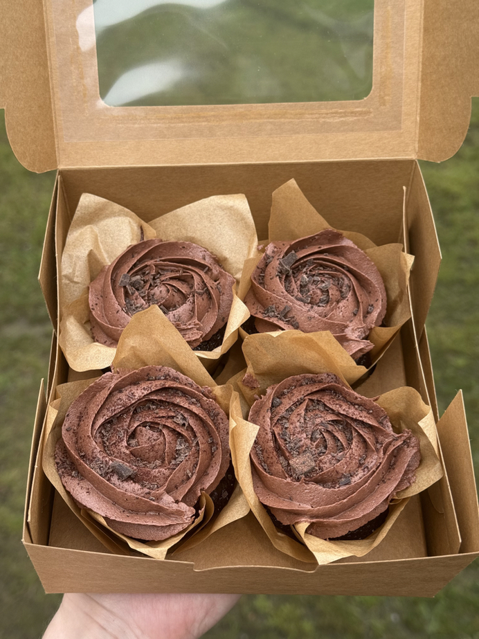 Four chocolate frosted cupcakes in a kraft bakery box